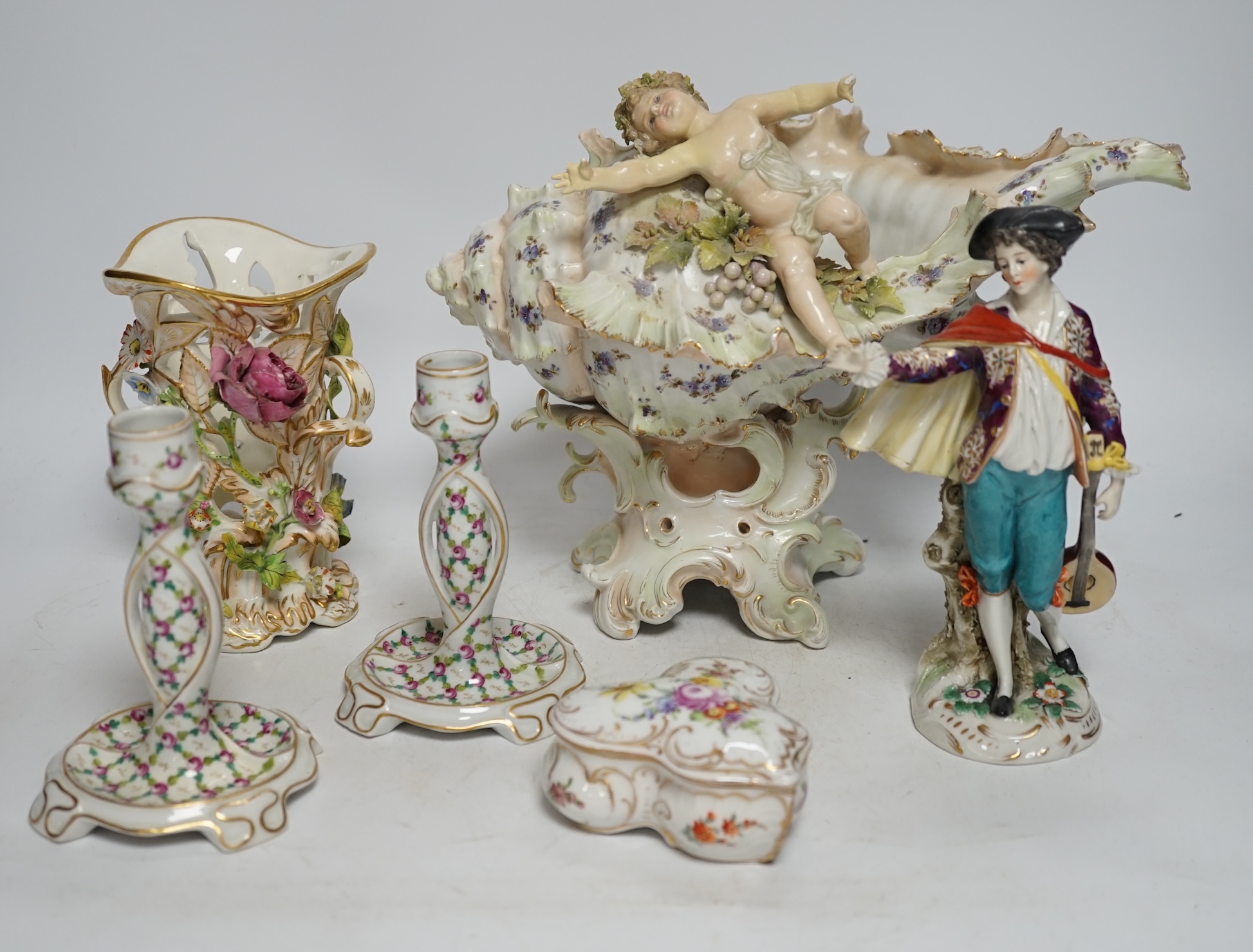 A porcelain shell-shaped centrepiece, a Dresden pill box, a pair of taper holders and a porcelain figure, tallest 21cm